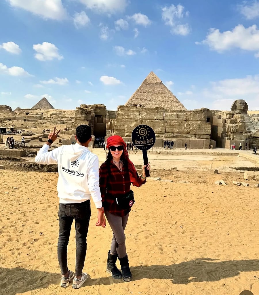 Nourbelle team member welcoming guests with a branded sign at the Sphinx and Giza Pyramids